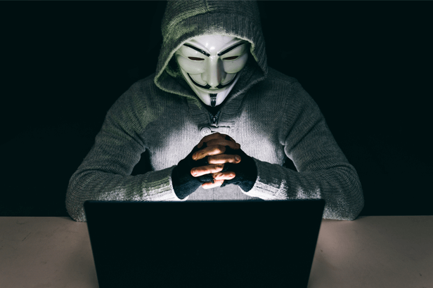 hacker membro do anonymous encarando um notebook - segurança digital